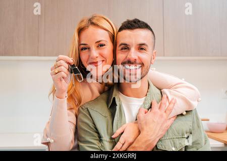 Kaukasisches Paar hält und zeigt den Schlüssel zu ihrer neuen Wohnung oder ihrem Haus vor die Kamera. Glückliche Menschen, die nach der Unterzeichnung einer Hypothek Eigentümer oder Mieter eines Grundstücks oder einer Wohnung sind. Eigentum. Hochwertige Fotos Stockfoto