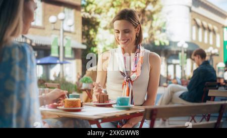 Begeisterte Freundinnen genießen köstliche Desserts in einem gemütlichen City Cafe. Porträt einer schönen jungen Frau, die ein Stück leckeren Schokoladenkuchen probiert, ihre Augen schließt und zufrieden lächelt Stockfoto