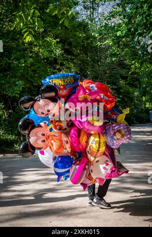 Straßenhändler, bedeckt von bunten Kinderballons im Nationalgarten, einem riesigen öffentlichen Park im Zentrum der Stadt, Athen, Griechenland Stockfoto