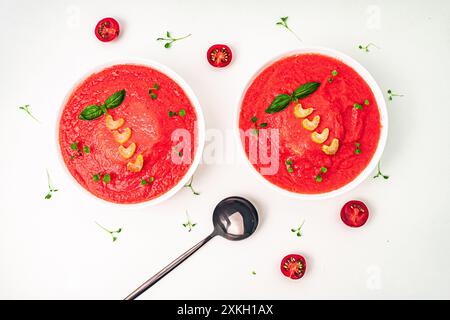Tomatenpüree-Suppe mit Basilikum und Sellerie auf hellem Hintergrund. Sauberes Essen, Diät, veganes Lebensmittelkonzept. Blick von oben. Hochwertige Fotos Stockfoto