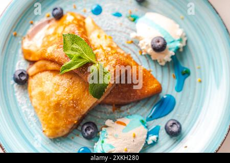 Crepes Suzette Pancakes mit Orangensauce, Mascarponenkäse und Heidelbeeren und Blue Curacao Topping. Ausgewählter Fokus. Hochwertige Fotos Stockfoto