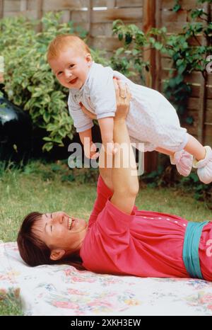 Familie. Mutter und Baby liegen auf einer Decke im Garten. Stockfoto