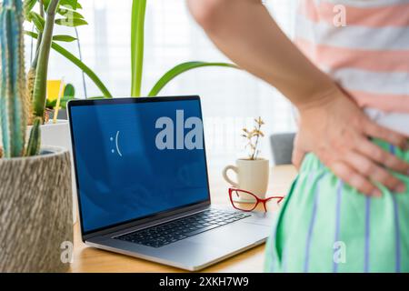 Verärgerte junge Frau, die auf traurigen Laptop-Monitor mit blauem Bildschirm auf dem Schreibtisch im Heimbüro schaut Stockfoto