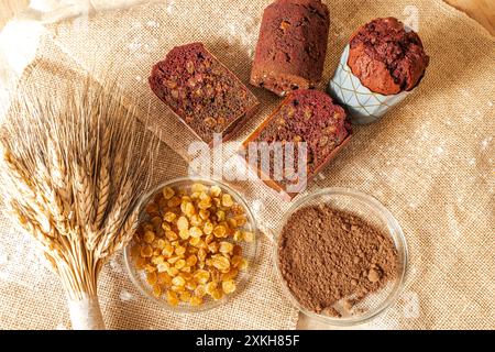 Muffins mit Heidelbeeren, Rosinen und Kakao auf Leinwand mit Weizenohren. Hochwertige Fotos Stockfoto
