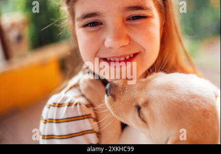 Nahporträt eines kleinen Mädchens, das einen Welpen umarmt. Ein süßes kleines Kind spielt mit einem Hund. Ein süßes Kind ist glücklich mit ihrem Haustier. Ein wunderbarer Vorschulgi Stockfoto