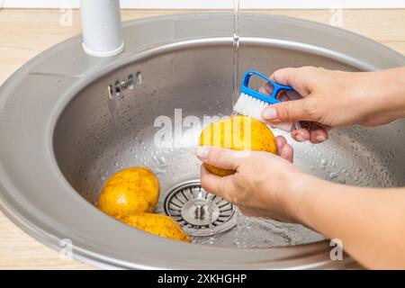 Die Hausfrau wäscht frische Kartoffeln in der Küchenspüle. Stockfoto