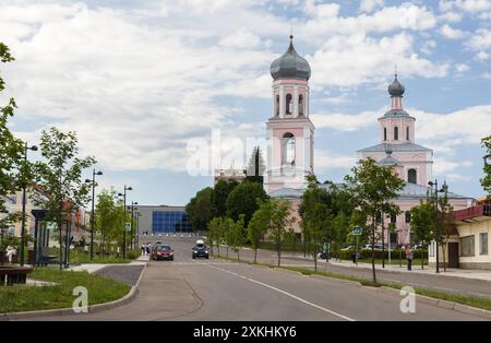 Valday, Russland - 6. Juli 2024: Straßenblick von Valday, Menschen gehen die Straße, Kathedrale der lebensspendenden Dreifaltigkeit im Hintergrund Stockfoto