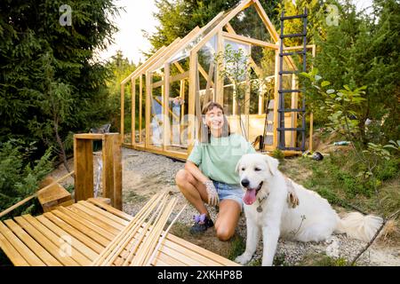 Eine Zimmerfrau mit ihrem Hund baut ein Holzgewächshaus Stockfoto