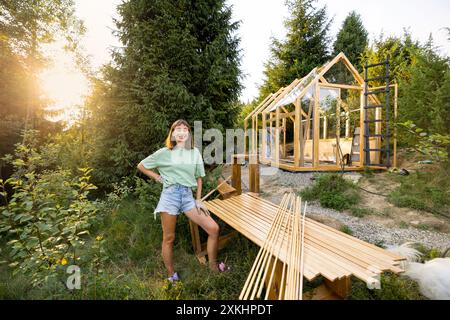 Zimmermann steht neben einem teilweise gebauten Holzgewächshaus Stockfoto