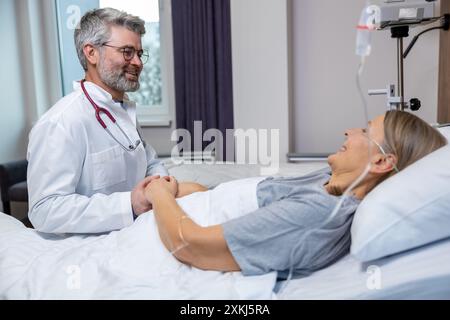 Doktor spricht mit einer Patientin und hält ihre Hände Stockfoto
