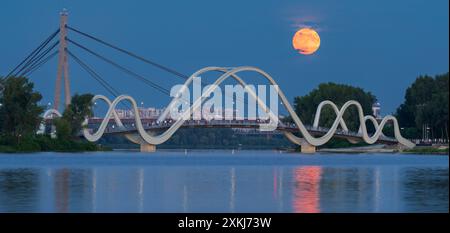 Die Menschen beobachten, wie der Buck Moon von einer Fußgängerbrücke aus in Kiew, Ukraine, über die Stadt aufsteigt. Stockfoto