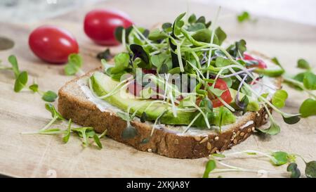 Eine einzelne Scheibe Vollkornbrot mit Mayonnaise, Avocado, Tomaten und einer Vielzahl von Mikrogemüse Stockfoto