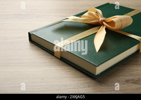 Buch gebunden mit goldenem Band auf Holztisch, Großaufnahme Stockfoto