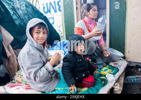 Mutter und Kinder im Dschungelmigrantenlager Dschungel. Eine Mutter und ihre beiden Kinder sitzen auf einer Decke vor ihrem Schuppen. Dunquerke, Frankreich. Duinkerken the Dschungel Nord Pas de Calais Frankreich Copyright: XGuidoxKoppesxPhotox Stockfoto