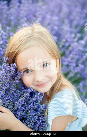 Porträt eines süßen 5-jährigen Mädchens mit braunen Augen in blauem Kleid. Glückliches Kind im Lavendelfeld. Stockfoto