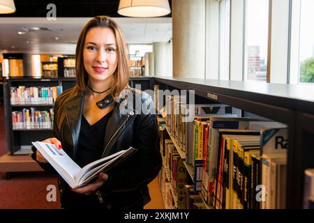 Junge Frau besucht Bibliothek Junge, brünette und kaukasische Immigrantin aus der Ukraine, Besuch der öffentlichen Bibliothek, um die niederländische Sprache zu lesen und zu lernen. Rotterdam, Niederlande. MRYES Rotterdam Openbare Bibliotheek Zuid-Holland Nederland Copyright: XGuidoxKoppesxPhotox Stockfoto