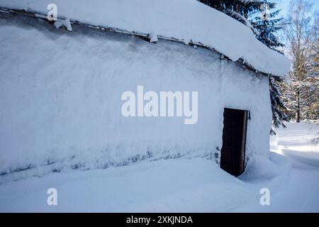 Holzscheune aus Baumstämmen im Winter, Wand mit Schnee bedeckt, Finnland Stockfoto