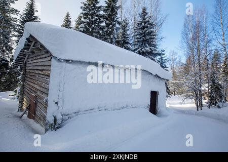 Holzscheune aus Baumstämmen im Winter, Wand mit Schnee bedeckt, Finnland Stockfoto
