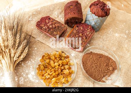 Muffins mit Heidelbeeren, Rosinen und Kakao auf Leinwand mit Weizenohren. Hochwertige Fotos Stockfoto