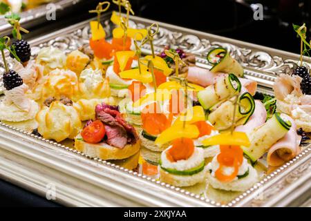 Eine exquisite Auswahl an Fingerfood auf einem silbernen Tablett mit verschiedenen kleinen Vorspeisen wie Käse, Walnüsse, Fleisch und Stockfoto