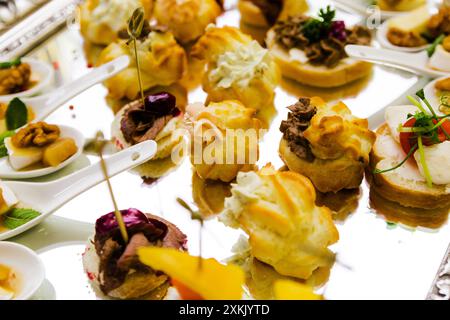 Eine elegante Präsentation verschiedener herzhafter Gebäckstücke und Häppchen auf einem dekorativen silbernen Tablett. Stockfoto