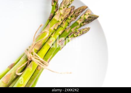 Ein Haufen roher Gartenspargel mit isoliertem Schatten. Frisches grünes Frühlingsgemüse auf weißem Hintergrund. Essbare Spargelsprossen, Draufsicht. Hohe Qual Stockfoto