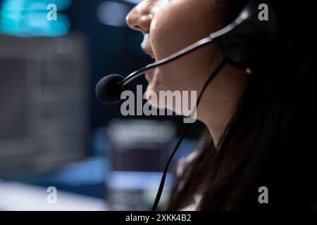 Support-Spezialist für Rechenzentren, der das Engineering-Team bei der Hardwarewartung unterstützt und über das Headset-Mikrofon spricht. Nahaufnahme des Mitarbeiters im Server-Hub, der Techniker mit Mikrofon koordiniert Stockfoto