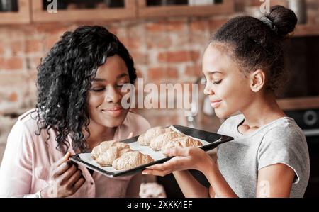 Fröhliches kleines Mädchen riechen selbstgemachte Croissants mit Mom Stockfoto