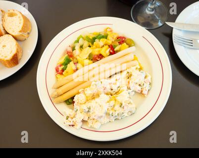 Spanischer Sommersalat und russischer Salat mit weißem Spargel auf Teller Stockfoto