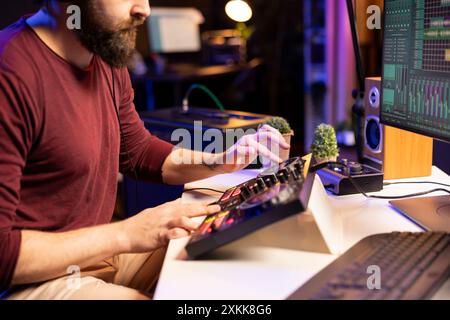 Musikproduzent kreiert neue Melodien auf der Mischkonsole durch Drehen der Vorverstärkerregler und Anpassen der Lautstärke im Heimstudio. Künstler Songwriter arbeitet an der Postproduktion mit Stereo-Ausrüstung. Stockfoto