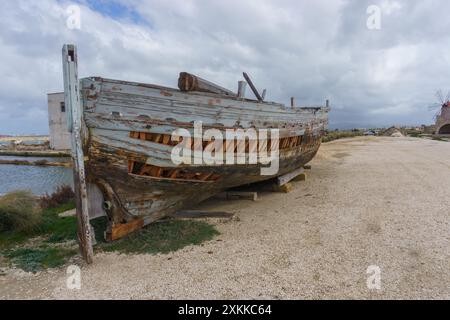 Altes beschädigtes Boot im Naturschutzgebiet Saline di Trapani mit Salzfeldern an einem bewölkten Tag, Contrada Nubia, Sizilien, Italien Stockfoto