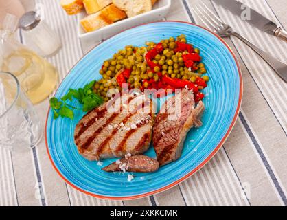 Ganzes Rindfleisch über offenem Feuer gekocht, mit appetitlicher Kruste und dunklen Streifen mit Paprika, Bohnen Stockfoto