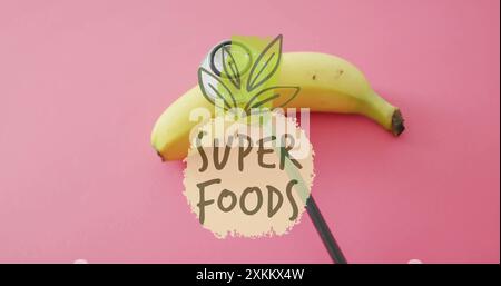 Superfood-Textbild über Banane auf rosa Hintergrund Stockfoto