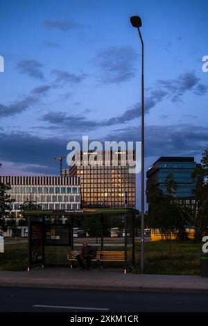 31.05.2024, Polen, Wielkopolska, Posen - Mann wartet an der Bushaltestelle Posen Glowny (Hauptbahnhof), hinter ihm Bürogebäude vor A Stockfoto