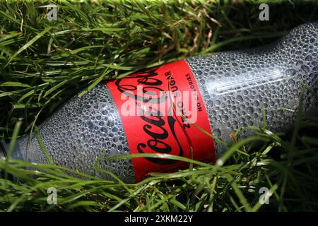 22.06.2023, Vereinigtes Königreich, Windsor, Ascot - Leere Koksflasche im Gras. 00S230622D234CAROEX.JPG [MODELLFREIGABE: NICHT ZUTREFFEND, EIGENSCHAFTSFREIGABE RE Stockfoto