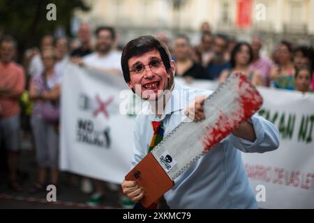 Madrid, Spanien. Juli 2024. Ein Demonstrant mit Maske und dem Gesicht von Jose Luis Martinez Almeida, Bürgermeister von Madrid, hält bei einer Demonstration gegen das Fällen von Bäumen auf der Plaza Santa Ana eine Säge. Der Madrider Stadtrat plant, 30 Bäume auf der Plaza Santa Ana in Madrid zu Fällen, um die Tiefgarage umzubauen. Quelle: SOPA Images Limited/Alamy Live News Stockfoto