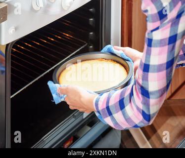 Hände der Hausfrau, die Käsekuchen aus dem Ofen in der Küche nimmt Stockfoto