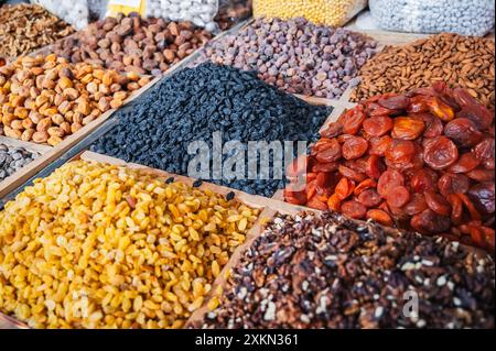 Verschiedene Sorten von getrockneten Früchten und Nüssen auf dem Theken des orientalischen usbekischen Lebensmittelbazars in Zentralasien. Rosinen, getrocknete Aprikosen, Mandeln, Walnüsse und Feigen im Marktstand Stockfoto