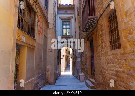 Barcelona, Spanien - 16. Juli 2024: Schmaler Durchgang in Barcelona mit antiken Steinmauern und architektonischen Details Stockfoto