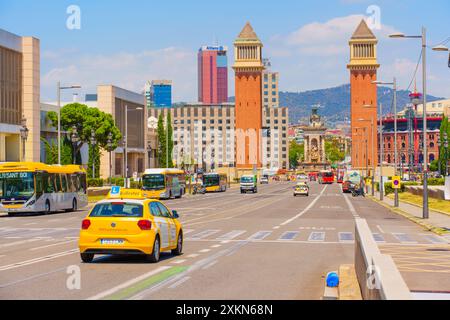 Barcelona, Spanien - 16. Juli 2024: Klassisches gelbes Taxi, das an der belebten Straße vorbei an berühmten Doppeltürmen in Barcelona fährt Stockfoto