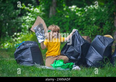 Ein Kind in Gummihandschuhen mit Müllbeutel reinigt Müll im Wald draußen. Umweltschutz. Umweltverschmutzung recyceln. Untergeordnetes Objekt sammelt Garbage and Stockfoto