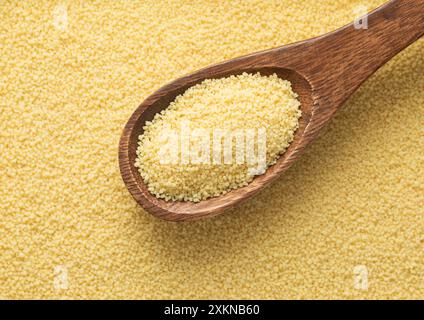 Gelbe rohe organische gesunde Couscous Körner Samen auf Holzlöffel strukturiert Hintergrund. Stockfoto