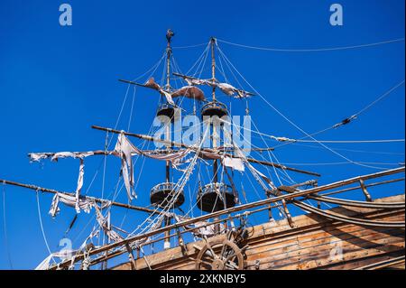 Mast mit weißen Segeln auf einem alten hölzernen Piratenschiff auf dem Hintergrund des blauen Himmels Stockfoto