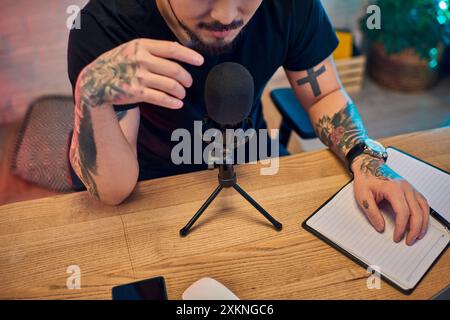 Ein tätowierter asiatischer Mann, der einen Podcast in seinem Studio aufnimmt. Stockfoto