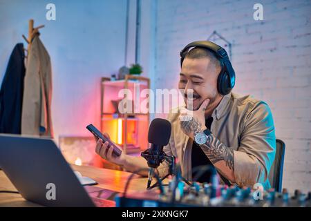 Ein asiatischer Mann lächelt, während er in seinem Studio einen Podcast aufnimmt. Stockfoto