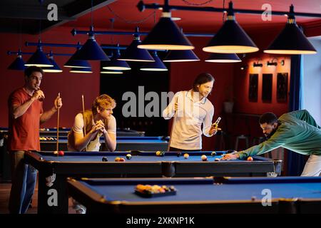 Freunde spielen eine Partie Billard in einer schwach beleuchteten Bar. Stockfoto