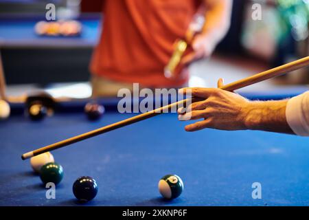 Eine Nahaufnahme einer Hand, die einen Pool-Queue hält und auf die Bälle auf dem Tisch zielt. Stockfoto