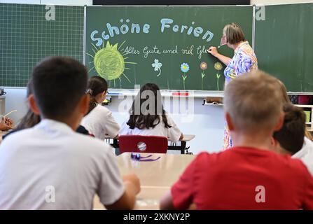 Stuttgart, Deutschland. Juli 2024. Schüler der 4. Klasse in Stuttgart sitzen am letzten Schultag vor den Sommerferien in Baden-Württemberg im Klassenzimmer, während ein Lehrer "schöne Ferien, alles Gute und viel Glück" an eine Tafel schreibt. Quelle: Bernd Weißbrod/dpa/Alamy Live News Stockfoto