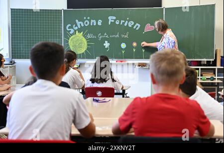 Stuttgart, Deutschland. Juli 2024. Schüler der 4. Klasse in Stuttgart sitzen am letzten Schultag vor den Sommerferien in Baden-Württemberg im Klassenzimmer, während ein Lehrer "schöne Ferien, alles Gute und viel Glück" an eine Tafel schreibt. Quelle: Bernd Weißbrod/dpa/Alamy Live News Stockfoto