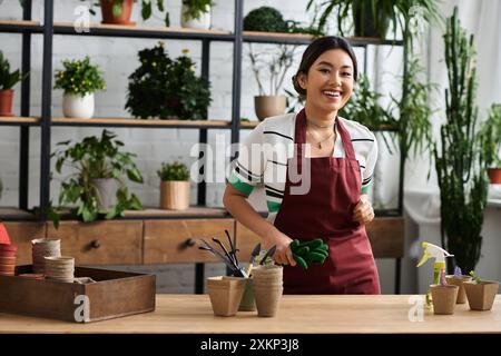 Eine asiatische Frau lächelt, während sie an einer Theke in ihrem Werk arbeitet. Stockfoto